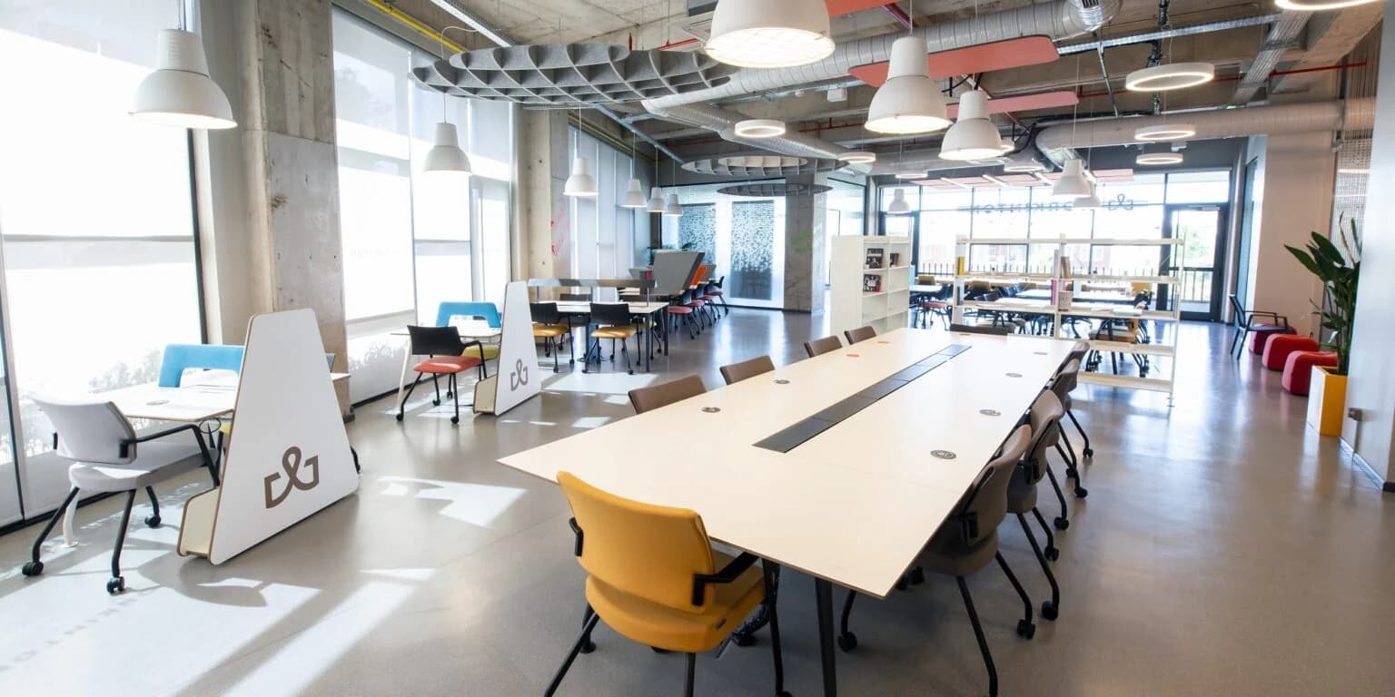 Geniş pencerelerle aydınlanan Workinton açık ofisi ve çalışma masaları